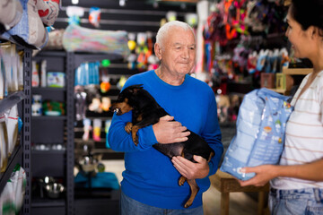 Pet store employee helps an elderly man choose dry dog food
