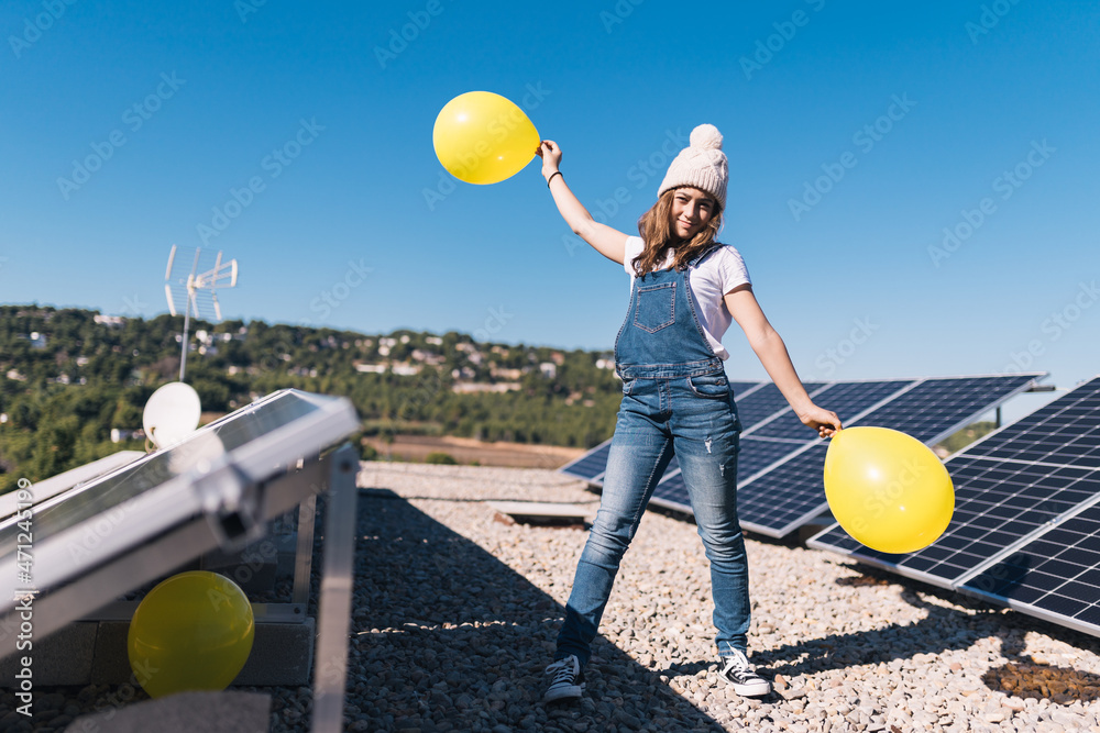 Wall mural happy teenage girl on the terrace next to the solar panels. sunny spring day. solar energy. ecologis