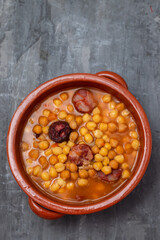 chick pea with smoked sausages and meat in brown pot