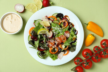 Concept of tasty food with vegetable salad with tahini sauce on green background