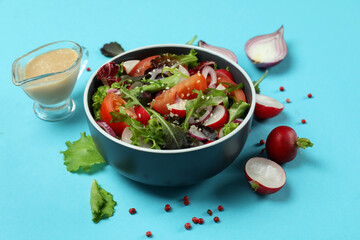 Concept of tasty food with vegetable salad with tahini sauce on blue background