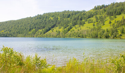 Landscape. Lake from a height among the green mountains against the backdrop of a cloudy sky. Lake Maloe, Siberia, Krasnoyarsk Territory, Russia,