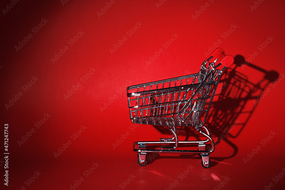 Wall mural an empty grocery cart casts a shadow over the red wall.