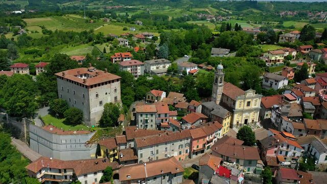 Aerial view around a village and the Montaldeo Castle, in Piemonte, Italy - circling, drone shot