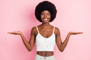 Photo of optimistic young curly hairdo lady hold empty space wear white top isolated on pastel pink color background