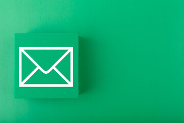 Email concept. Envelope drawn on toy square against dark green background with copy space. Concept...