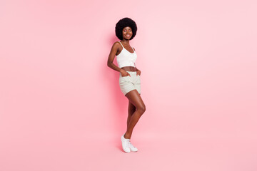 Fototapeta na wymiar Full size photo of sweet young curly hairdo lady wear white top shorts isolated on pastel pink color background