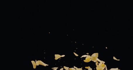 Natural potato chips rise and fall against a black background. Slow Motion 300 fps Blackmagic Ursa Pro G2.