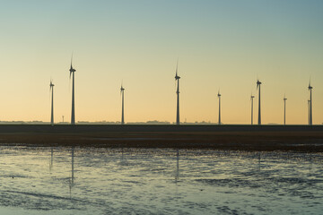 Wind turbines spinning at the Dutch coast on a sunny afternoon.
