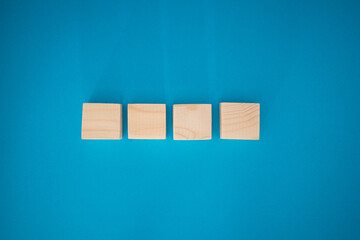Top view of blank four wooden cubes on a blue background with space for text