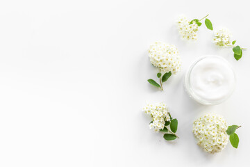 Fototapeta na wymiar White blossoms flowers with skin cream in glass jar