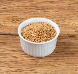 Golden linseed on a bowl over wooden table