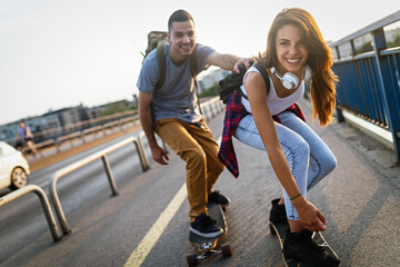 Portrait of happy couple riding skateboards and having fun outdoors. Teenager happiness concept