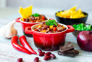 Delicious chili con carne in red pots served with a side of tortilla chips