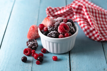 Assortment of iced berries in a bowl on blue wooden table	