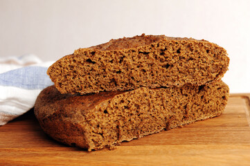 Fresh homemade round malted rye bread on wooden board. White background, linen fabric