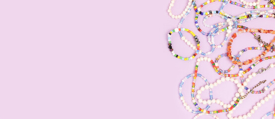 Necklaces and bracelets made from multicolored beads and pearls on a purple background with...