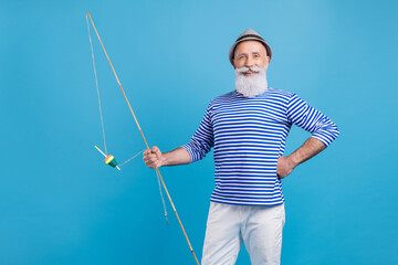 Portrait of attractive skilled cheerful grey-haired man holding rod sea rest isolated over bright blue color background