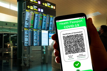 A Covid certificate, also called covid passport, is seen on the screen of a mobile phone with an airport in the background. More and more countries are adopting the Covid19 vaccination passport