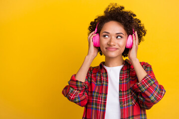 Portrait of attractive minded cheerful girl listening pop single thinking copy space isolated over bright yellow color background