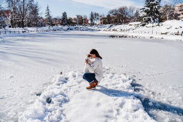 caucasian woman hugging cute jack russell dog while standing on snowy pier by frozen lake during...