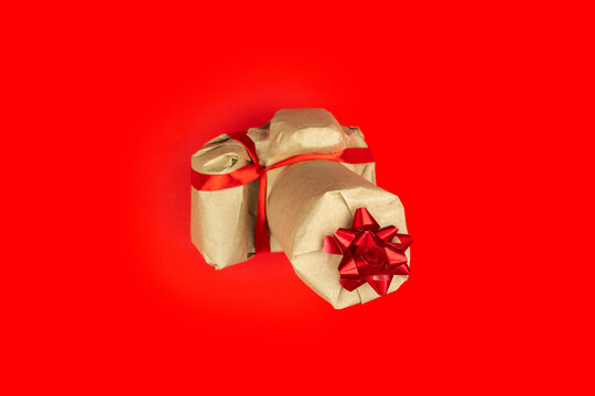 Eco rustic beige recycled Christmas new year gift, photo camera wrapped in craft paper with red ribbon on red color background. Holiday present. Care package. Vintage parcel. Festive congratulation.