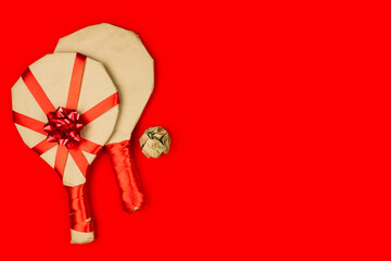 Eco rustic beige recycled Christmas new year gift, tennis racket wrapped in craft paper with red...