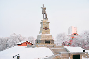 Monument to General Governor-General of Eastern Siberia Nikolai Nikolaevich Muravyov-Amursky in Khabarovsk in the morning at sunrise. There are trees in the snow all around.