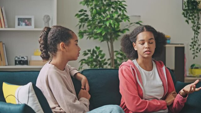 Serious african american teen girls discussing problem, conflict between friends