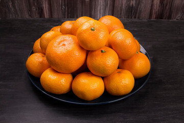 Fresh tangerines fruit or tangerines with leaves on a plate.