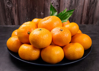 Fresh tangerines fruit or tangerines with leaves on a plate.
