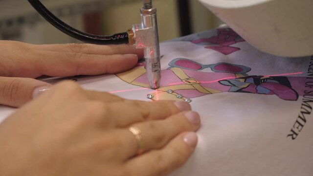 The process of applying rhinestones to clothes using an industrial machine.