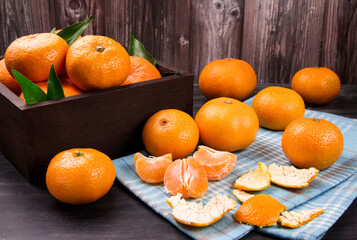 Fresh mandarin oranges fruit or tangerines with leaves in the wooden box.