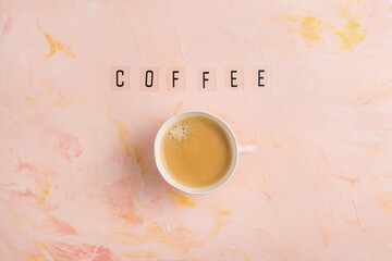 Cup of espresso coffee and text COFFEE on pastel pink background. Flat layout, top view, copy space