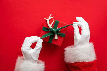 Santa Claus holding a wrapped gift box present against a red background