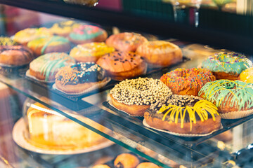 Delicious donuts decorated with different decorations displayed in cafe glass cabinet. Selective...