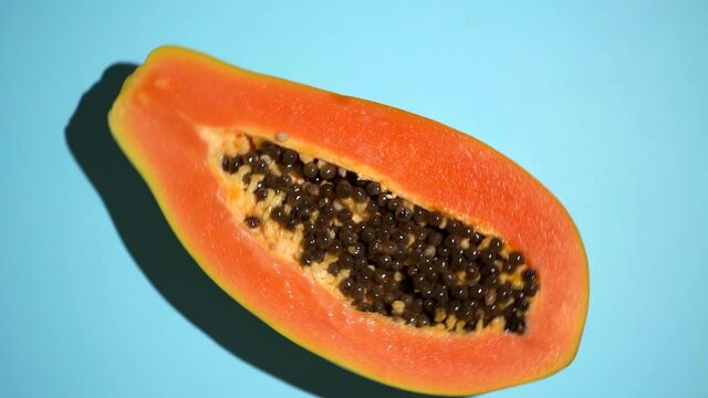 Tropical fruit papaya rotates on a colored sunny background. Summer, vitamins, food, juice, minimal concept