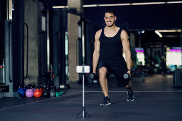 Naklejka na ściany i meble Arab Male Fitness Coach Capturing Training Videos At Gym For His Blog