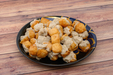 Fried Fish Tofu placed in a black plate and put on the wooden table.
