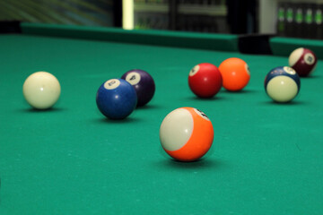 Billiard balls on green table and orange ball