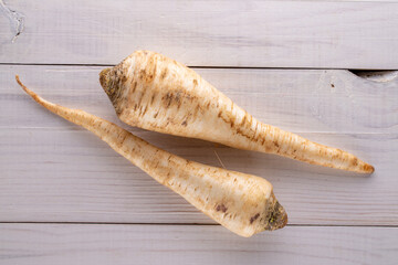 Two fragrant parsnip roots on a wooden table, close-up, top view. - obrazy, fototapety, plakaty