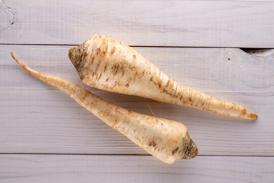 Two fragrant parsnip roots on a wooden table, close-up, top view.