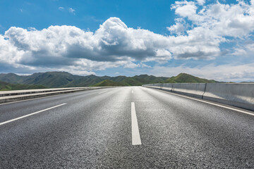 Asphalt road and green mountains under blue sky