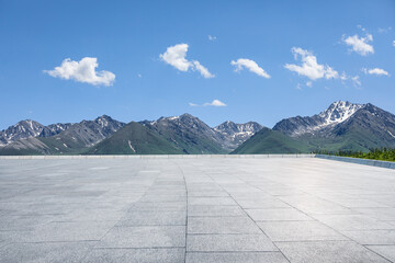 Empty square floor and mountains under blue sky. Road and mountain background.