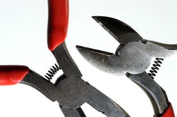 nippers and pliers with red handles on a light background close-up.