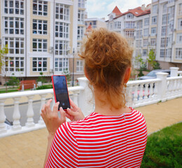 a girl in a red dress with white stripes takes pictures of city buildings on her smartphone. the...