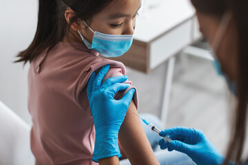 Nurse Injecting Covid-19 Vaccine Vaccinating Korean Little Girl Sitting Indoor