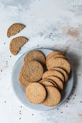 Plate with tasty crackers with sesame and flax seeds on grey stone background. Top view.