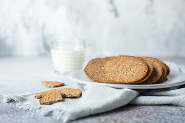 Plate with tasty crackers and a cup of milk. Snack or breakfast on grey stone background.