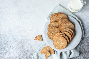 Plate with tasty crackers and a cup of milk. Snack or breakfast on grey stone background. Top view.
